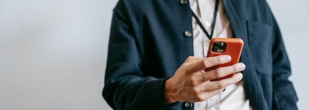 A man in casual attire browsing on a smartphone indoors, showcasing modern tech lifestyle.